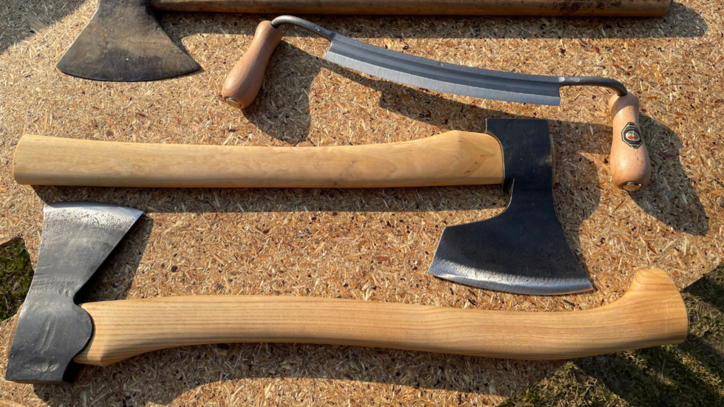 Zestaw ręcznie kutych narzędzi do obróbki drewna, w tym siekiery w stylu wikińskim oraz narzędzie typu ośnik.